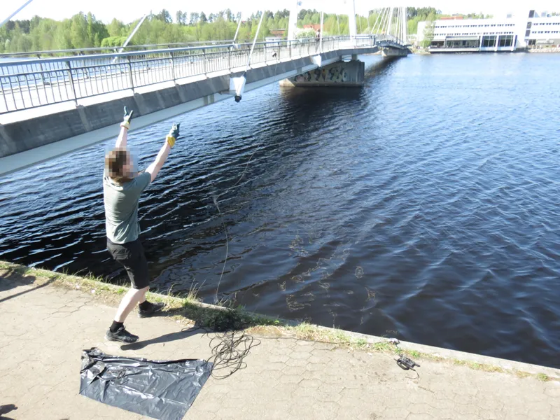 A person magnet fishing from a bridge in Finland
